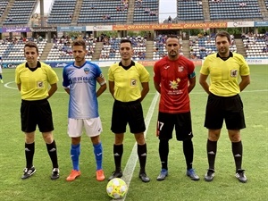 El trío arbitral junto a los capitanes del CF La Nucia y el Lleida